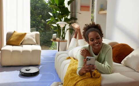 A woman using her phone to set up the Roborock S7 MaxV Ultra for cleaning